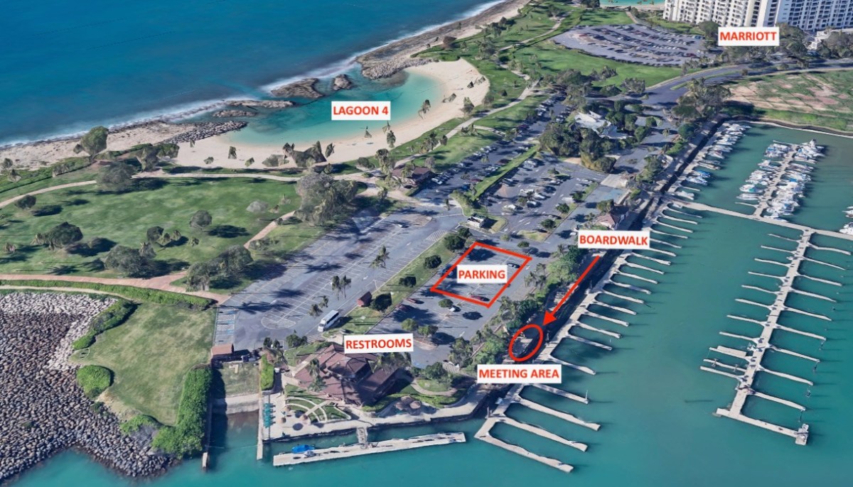 Aerial view of parking lot, boardwalk, and marina near a beach lagoon.